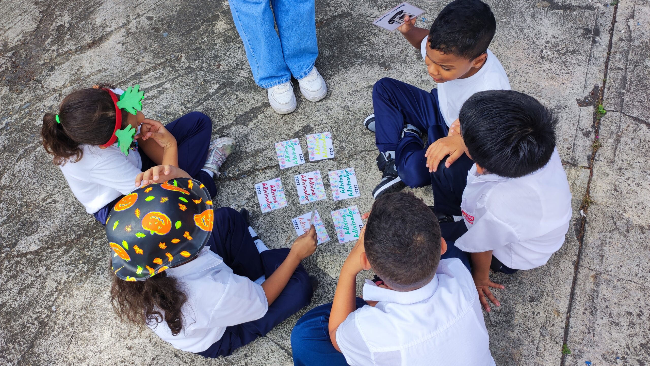 Niños jugando juntos alrededor de unas cartas de papel en medio de una dinámica navideña.